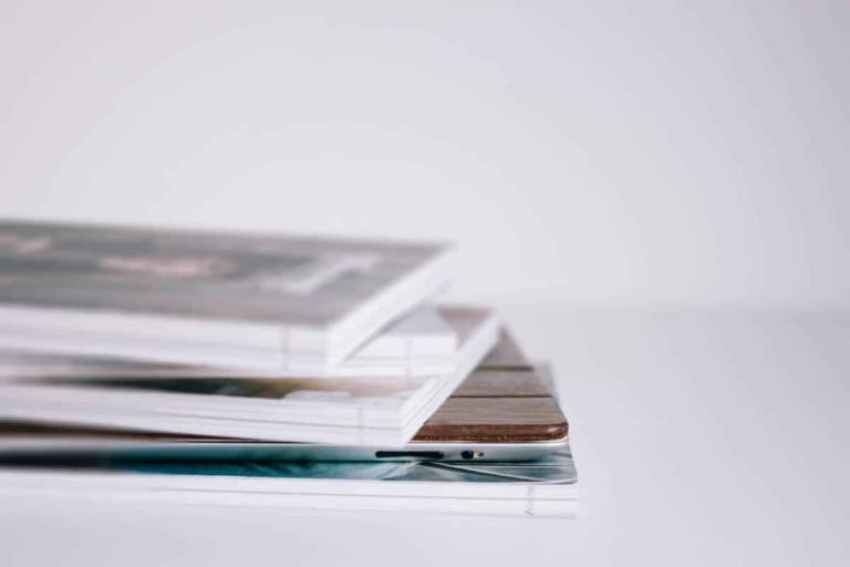 Vue rapprochée de magazines ou livres empilés sur une surface blanche, fond blanc, formation Gestalt thérapie.