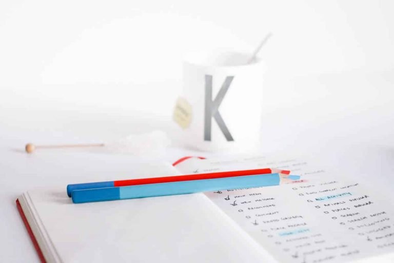 Deux crayons de couleur sur un carnet à checklist, tasse et sucre, lors d'une formation Gestalt-thérapie.