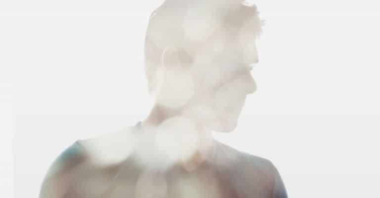 Silhouette d'une personne de profil, partiellement obscurcie et légèrement éclairée, avec des points lumineux flous au premier plan, créant un effet éthéré et rêveur, évoquant les thèmes de la découverte de soi et de la connexion que l'on retrouve dans la thérapie Gestalt.