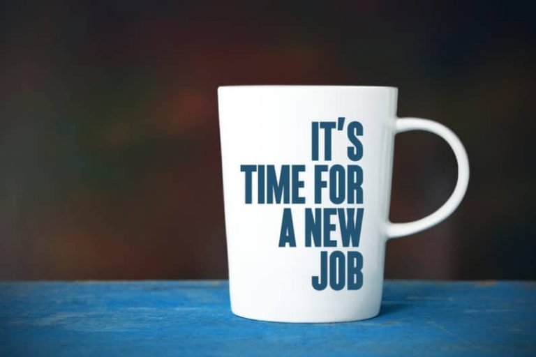 Une tasse à café blanche avec les mots ITS TIME FOR A NEW JOB imprimés en caractères gras bleu foncé, placés sur une surface bleue - un accessoire parfait pour tout praticien de la Gestalt ou étudiant de l'École Humaniste de Gestalt qui réfléchit au changement.