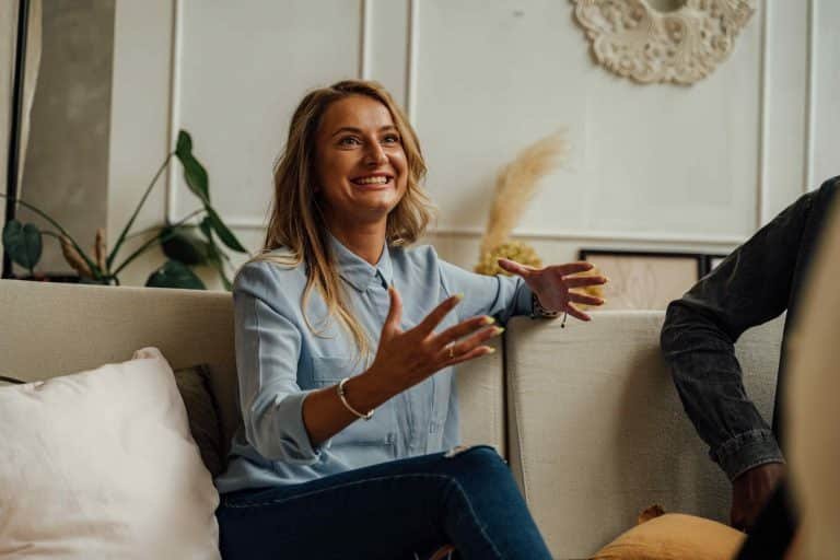 Une femme souriante échange avec une personne assise en face d’elle.