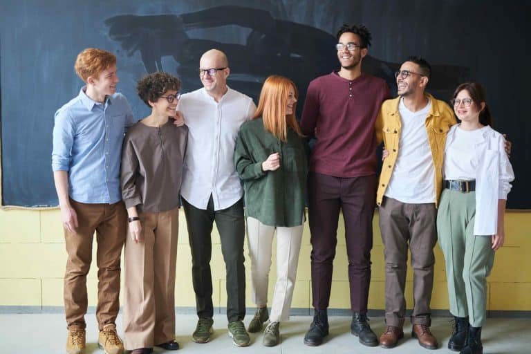 Un groupe de personnes se tient côte à côte devant un tableau.
