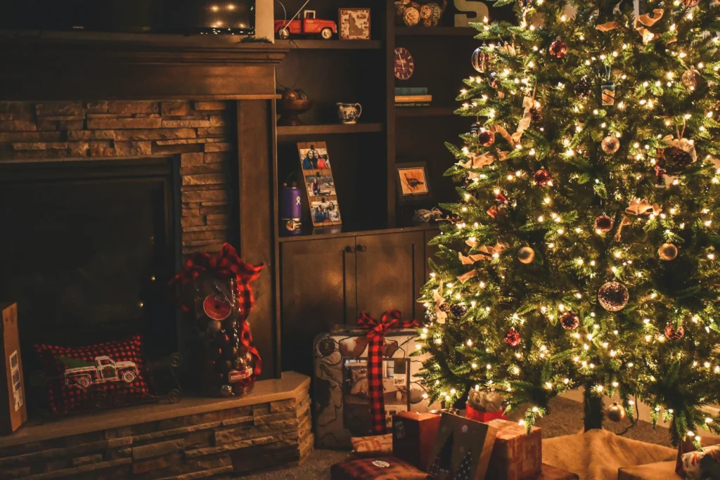A warmly lit living room with a decorated Christmas tree, wrapped presents beneath it, and a stone fireplace radiates a cozy holiday atmosphere, perfect for reflecting on moments of togetherness and the nuances of dépendance affective.