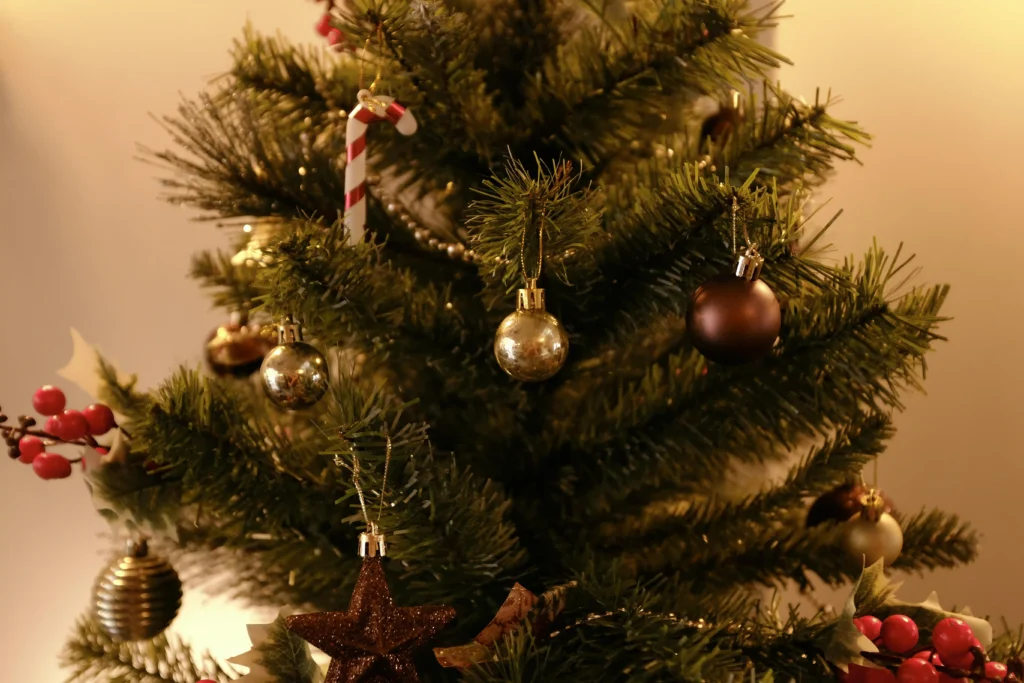 A close-up of a decorated Christmas tree with gold and brown ornaments, a candy cane, and festive berries. The warm lighting creates a cozy atmosphere, perfect for fêtes and holiday gatherings.