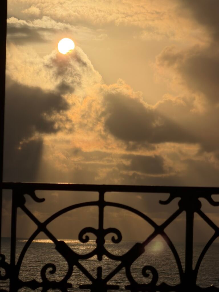 Soleil voilé par les nuages derrière une balustrade en fer forgé